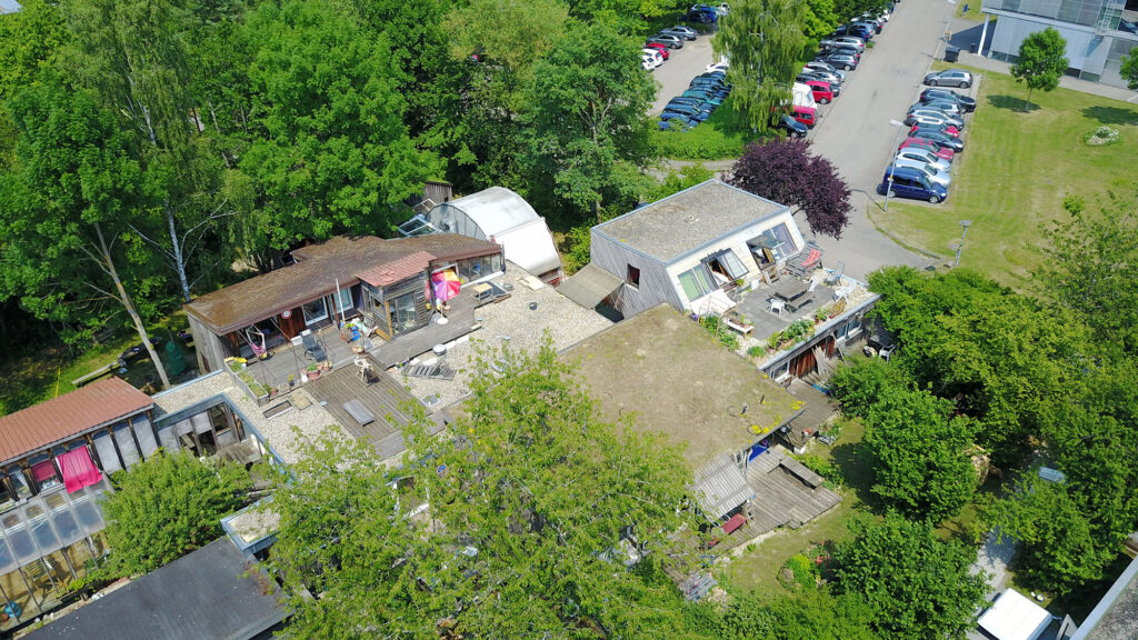 Drohnen-Aufname des Dachs. Ein verwinlelter Bau umrandet von Bäumen.