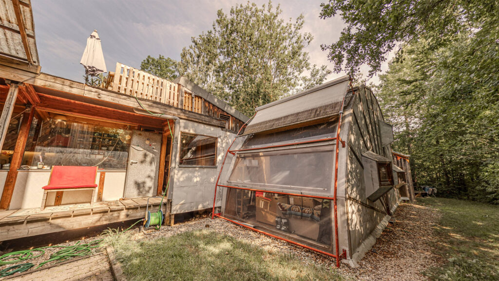 Foto vom Nordgang-Eingang des Häusles. Die Eingangsterrasse mit Tür links und rechts die Glasfassade des Camembert-Halbkreises