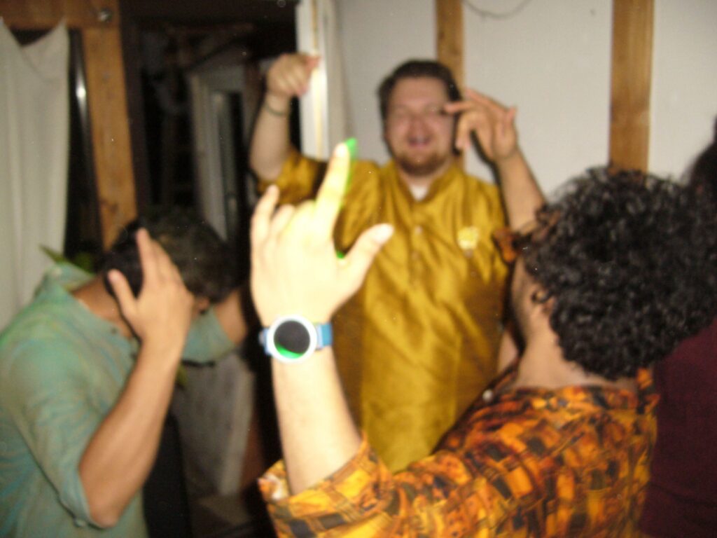 Verschwommene Aufnahme von drei Studenten die in einem Zimmer tanzen und feiern.